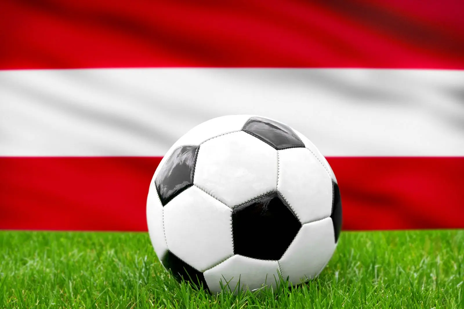 Fußball vor der österreich-fahne, symbolisierend die österreichische nationalmannschaft und den fußball.