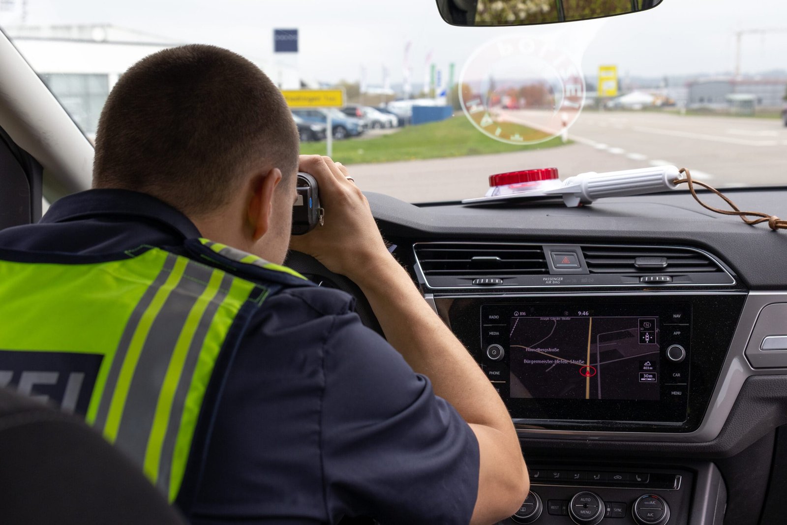 Blitzermarathon 2026: bayern richtet den blick auf gefährliche landstraßen 2 polizist lasermessung scaled Blick über die schulter eines polizisten im streifenwagen, der mit einem handlasermessgerät die geschwindigkeit auf einer landstraße kontrolliert