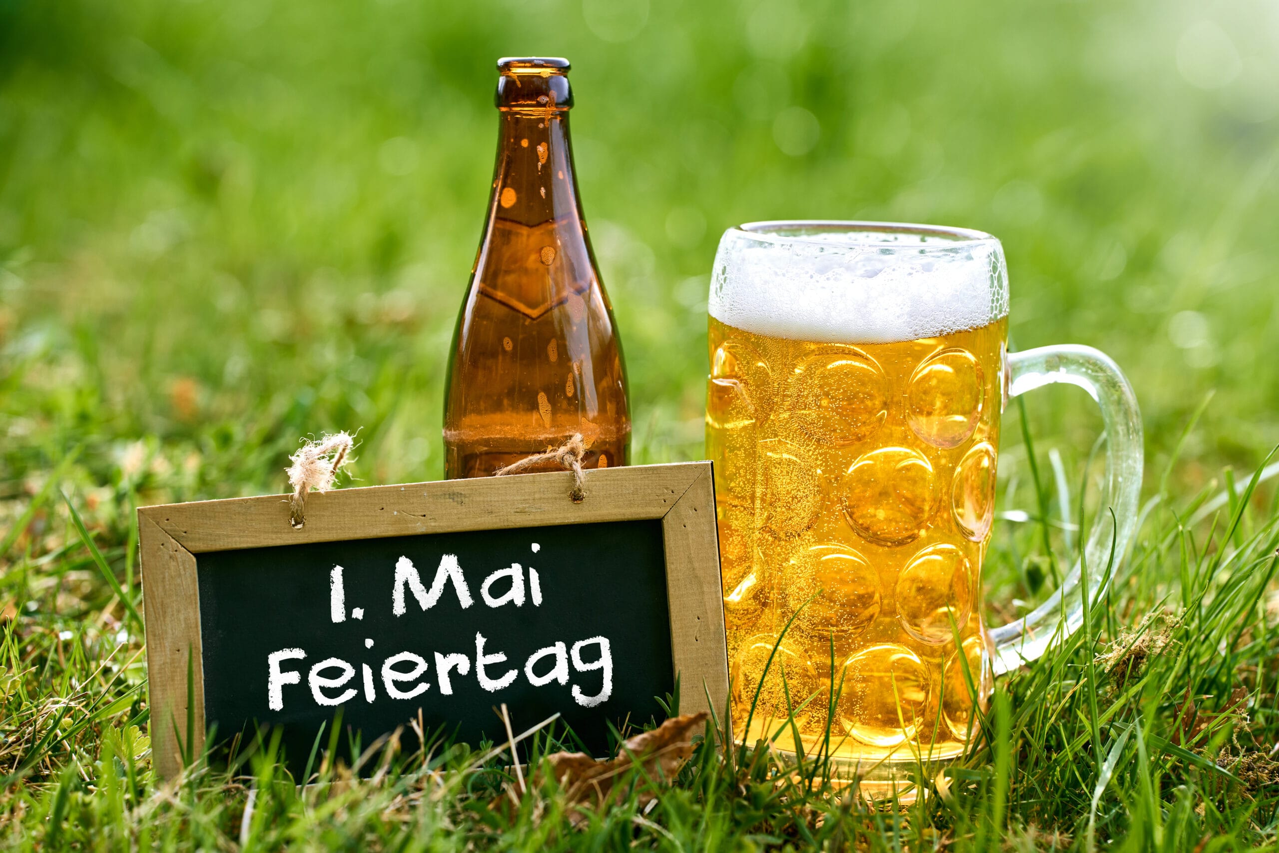 Tafel in einer grünen wiese mit einem bierkrug mit schriftzug: 1. Mai feiertag